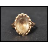 A hallmarked 9ct gold and smokey quartz dress ring set with a large oval cut smokey quartz in a