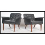 A pair of vintage danish influence mid 20th century, circa 1960's black faux leather armchairs.