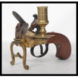 A good copy of a brass flintlock tinder lighter, scroll engraved frame with lyre stand and turned