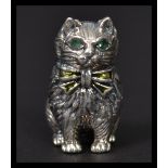 A sterling silver miniature figurine of a cat having emerald inset eyes. Weighs 17 grams.