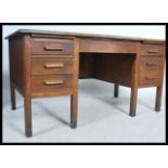 A mid century Air Ministry style oak twin pedestal desk raised on squared legs with a series of