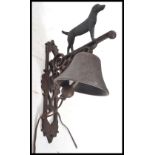 A vintage cast iron wall mounted bell in the form a standing black dog. Measures 35 cm high.