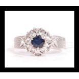 A hallmarked 18ct white gold sapphire and diamond ring having a central dark blue sapphire with a