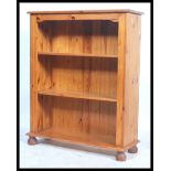 An antique style 20th century pine open window bookcase cabinet raised on bun feet with flared