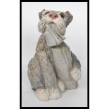 A 20th century stone dog figurine modelled with chewed newspaper in mouth. Measures 31 cm high.