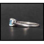 A hallmarked 9ct white gold ring set with a cushion cut pale blue stone flanked by two round cut