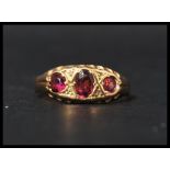A hallmarked 18ct gold and three stone ring having oval cut amethyst in a gypsy setting.