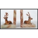 A pair of early 20th century vintage bookends in the form of cold painted cast metal stags raised on