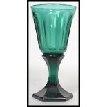 A stunning 19th century green glass wine glass having a conical bowl with slice cutting raised on