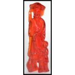 A 20th century red resin Chinese figurine of a fisherman giving a carp to a boy. Please see