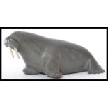 An Inuit / Eskimo soapstone carving of a walrus with two walrus ivory tusks. Signed to base B.I. ( B