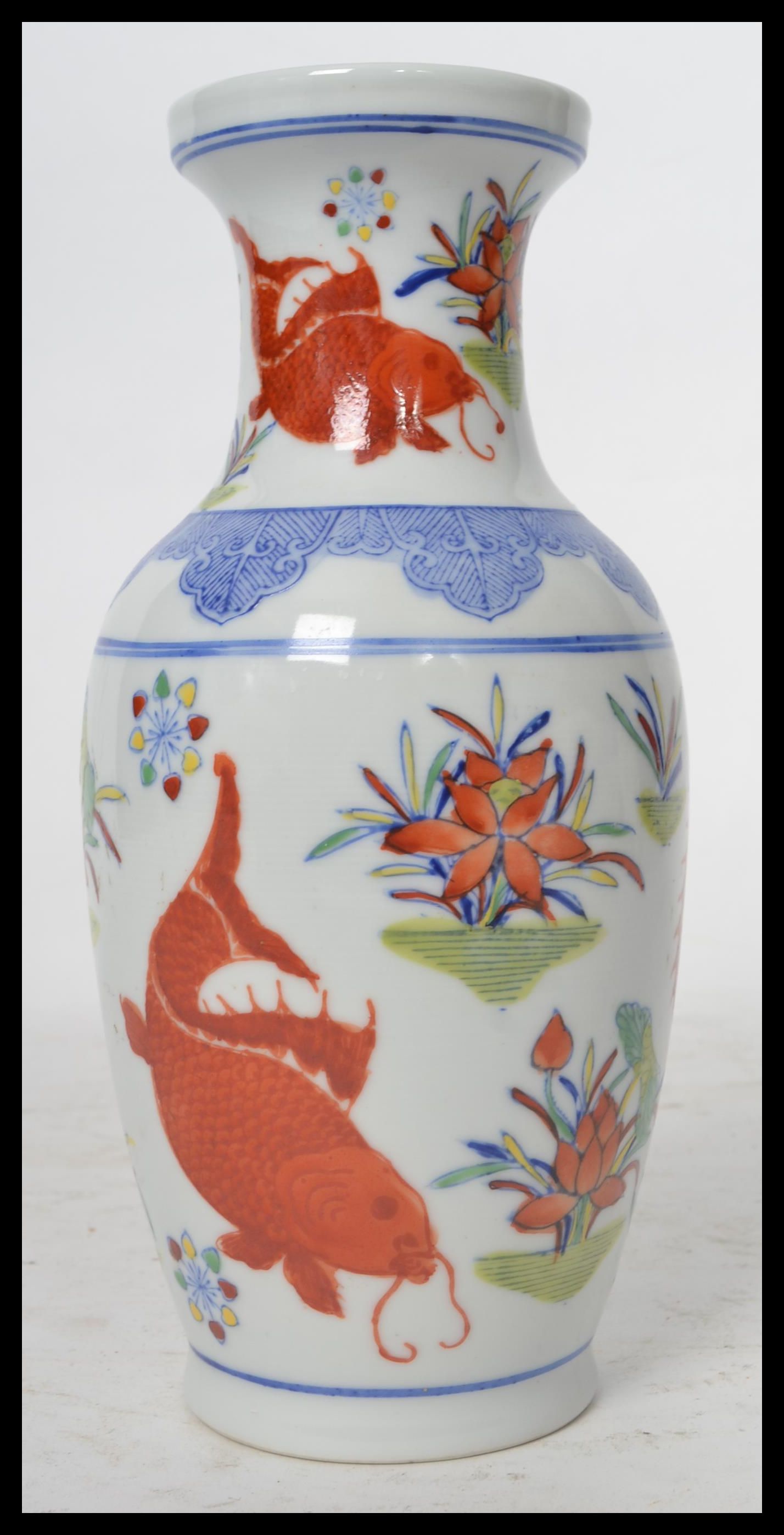 A 20th century Chinese vase decorated with scenes of carp and weeds with ochre red character marks