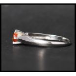 A hallmarked 9ct white gold solitaire ring set with a single round cut orange stone. Hallmarked