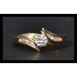 A 14ct gold and diamond crossover ring having a central prong set diamond with 8 diamonds to the