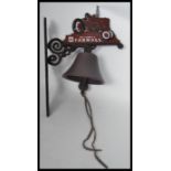 A vintage cast iron wall mounted bell in the form of a Farmall tractor. Measures 36 cm high.