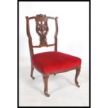 An Edwardian mahogany nursing chair having a pierced vase back with overstuffed seat raised on