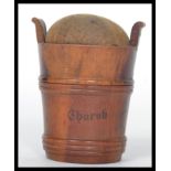 A 19th century treen pin cushion in the form of a bucket with twist off lid and baize cushion