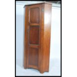 A 1930s 20th century oak bachelors corner wardrobe, having a full length panel door opening to