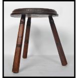 A 19th century carved oak spinning stool raised on tripod legs with carved floral medallion to the