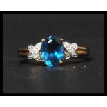 A hallmarked 9ct gold diamond and topaz ring having a central oval cut blue topaz flanked by diamond