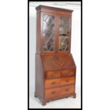 An Edwardian mahogany Liberty & Co of London bureau bookcase. The twin door bookcase cabinet with