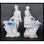 A pair of 19th century parian ware figurines of a dandy gent and a maiden raised on cornucopia spill