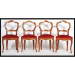 A set of four 20th century Victorian style mahogany balloon back dining chairs having overstuffed