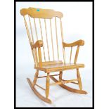 A 20th century beech farmhouse rocking chair with spindle back, scroll arms and solid seat base.