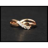 An 18ct gold and white stone ring set with five white stones in s crossover setting. Marks to