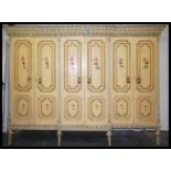 An early 20th century large painted Italian breakfront wardrobe being raised on turned legs with