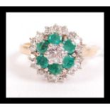 An 18ct gold emerald and diamond cluster ring having a central 20 point diamond with a halo of