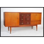 A retro 1970's teak wood sideboard dresser being raised on tapering legs with drawers and