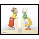 A pair of vintage mid 20th century ceramic bookend of a boy and girl in the manner of Hummel stamped