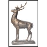 A vintage cast iron figurine of a deer stag with antlers raised on a naturalistic base. Measures