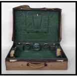 An early 20th century fitted leather suitcase with glass and silver metal vanity accoutrements