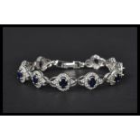 A silver CZ and sapphire panel bracelet having a fold over clasp. Weighs 13.9 grams size 8 inches.