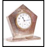 An early 20th century silver hallmarked desk top clock having a sloped base. The clock of pentagonal