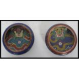 A pair of early 20th century circa 1900 Chinese cloisonne prayer bowls depicting dragons chasing the