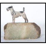 An early 20th century cold painted metal figurine of a terrier dog raised on a stone base.