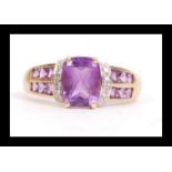 A hallmarked 9ct gold diamond and purple stone set ring. The ring having a large central cushion cut
