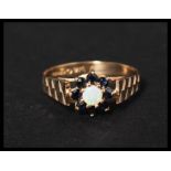 a hallmarked 9ct gold blue sapphire and opal ring set with a central opal surrounded by a sapphire