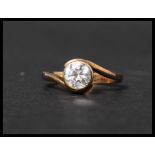 A hallmarked 9ct gold solitaire ring with a large white stone in a crossover bezel setting.