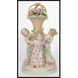 A 20th century ceramic diorama figurine of the Three Graces surrounding a plinth column with