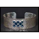 A sterling silver arts and crafts style bangle bracelet having a hammered design with an enamel