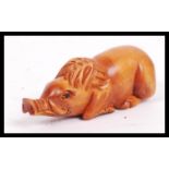 A 20th century carved Japanese netsuke in the form of a seated pig.