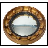 An early 20th century gilt framed ships mirror of circular form. The nautical themed mirror having