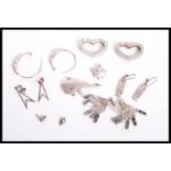 A collection of silver to include a pair of silver atomic earrings, silver whale brooch, silver leaf
