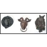 A group of three cast iron door knockers one in the form of a lion one being a ram and one being a