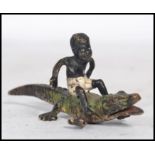 An early 20th century Austrian cold painted bronze figure of a young black boy sat upon the back