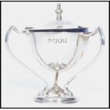 An early 20th century silver hallmarked three handledmustard pot condiment with blue glass liner